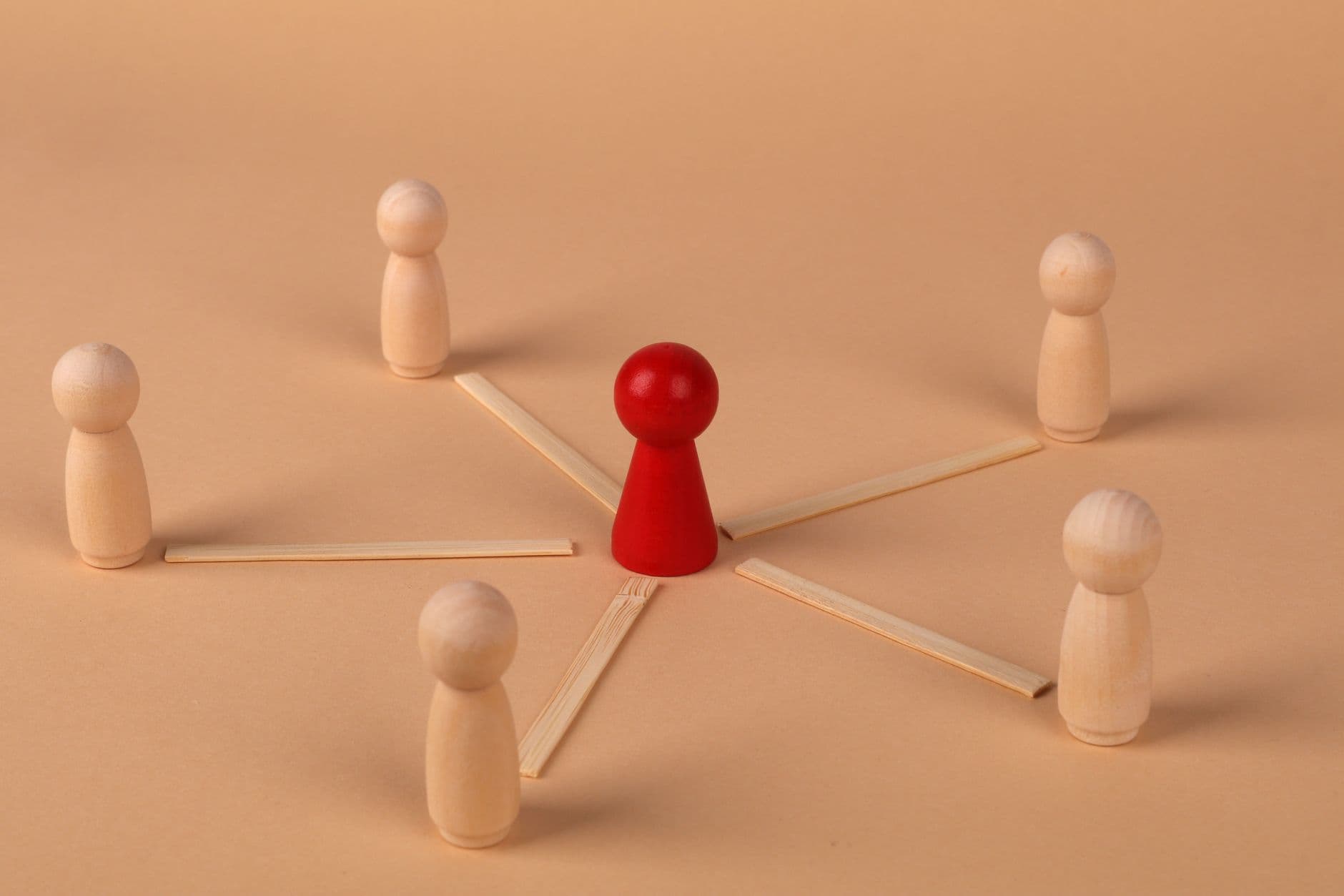 Wooden figures with red leader representing teamwork and influence.