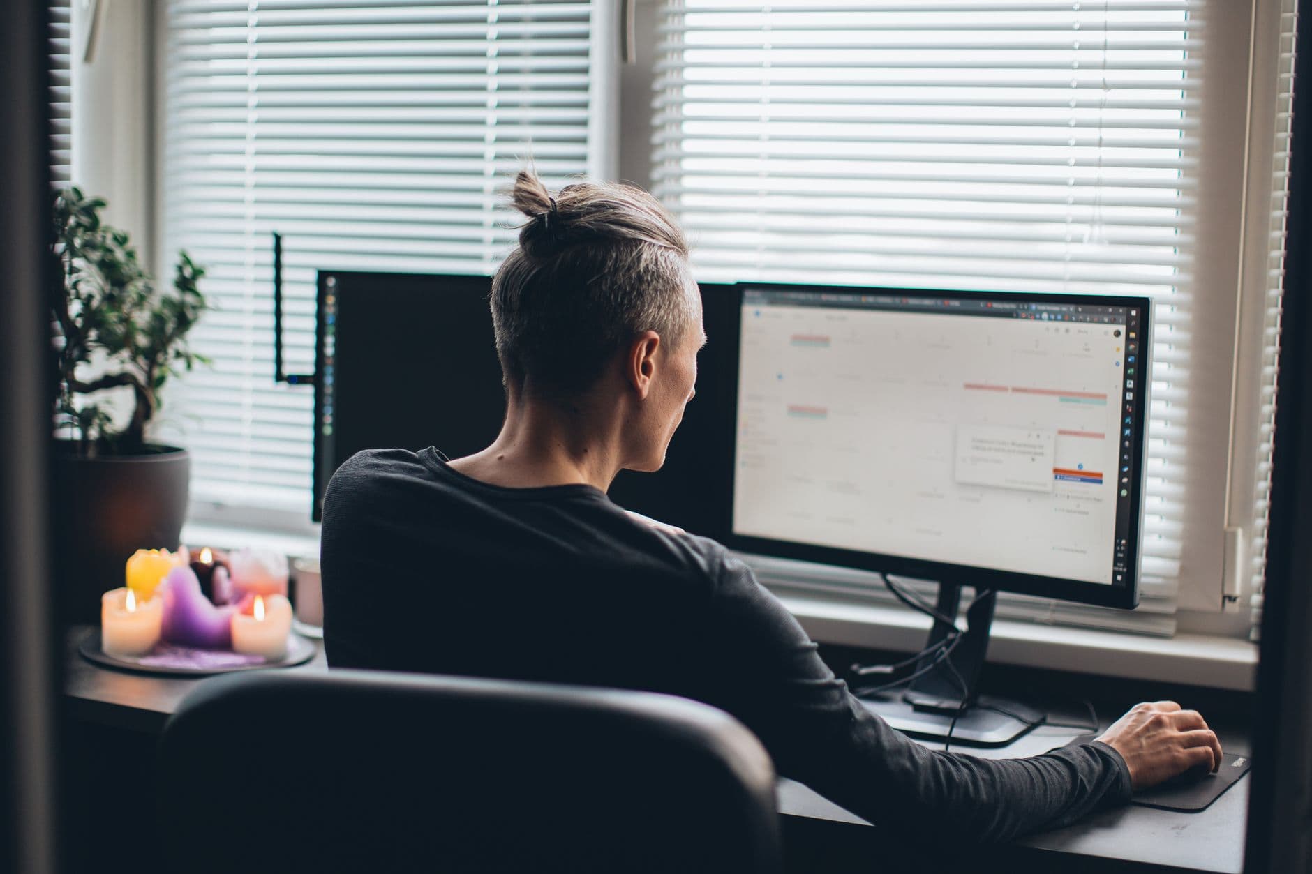 A man working remotely in a modern home office with dual monitors and ambient lighting.