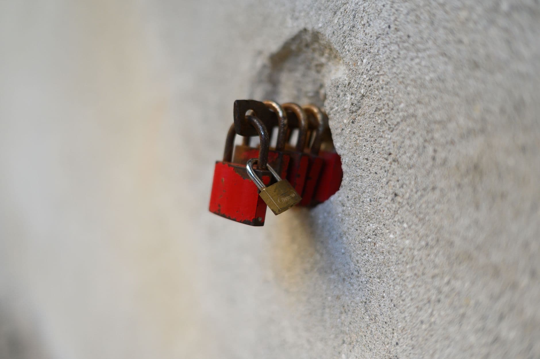 A series of red padlocks attached to a stone wall, symbolizing security and love.